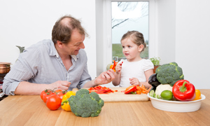 Un adulto prepara un'insalata insieme a un bambino